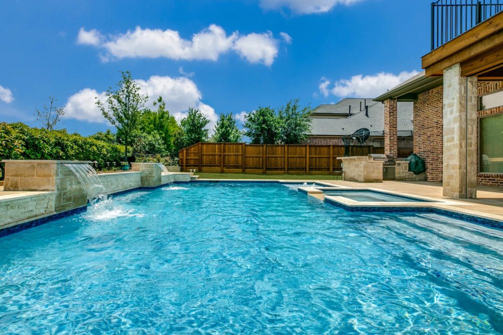 6da3b2_fec7e4ef4c5446b3ad19b2171268313c_mv2_d_3000_2000_s_2 A backyard swimming pool with a waterfall feature.