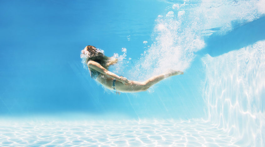 Woman in a blue swimsuit swimming underwater.